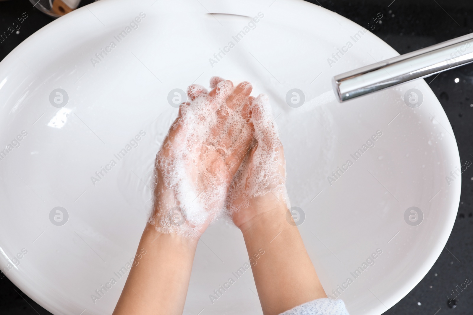 Photo of Woman washing hands with soap over sink in bathroom, top view