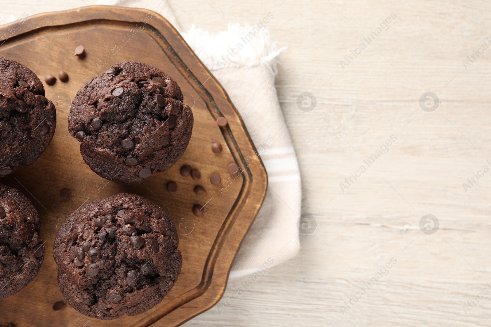 Photo of Delicious chocolate muffins on white wooden table, top view. Space for text