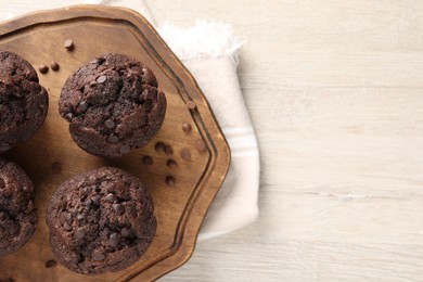 Delicious chocolate muffins on white wooden table, top view. Space for text