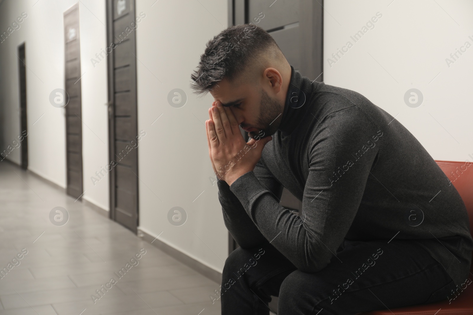 Photo of Sad young man in hall. Space for text