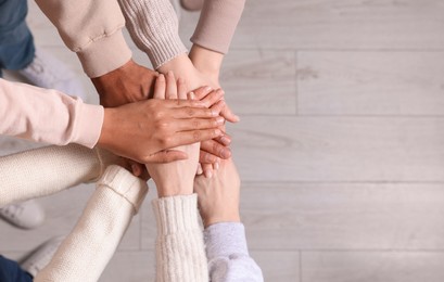 Photo of Group of multiracial people joining hands together indoors, top view. Space for text