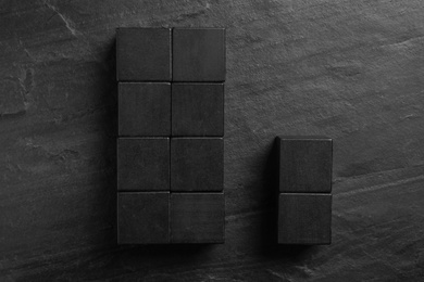 Flat lay composition with cubes on black slate background. Pareto principle concept
