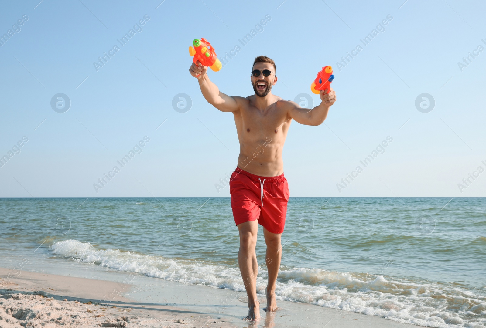 Photo of Man with water guns having fun on beach