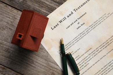 Photo of Last Will and Testament with fountain pen and house model on wooden table, top view