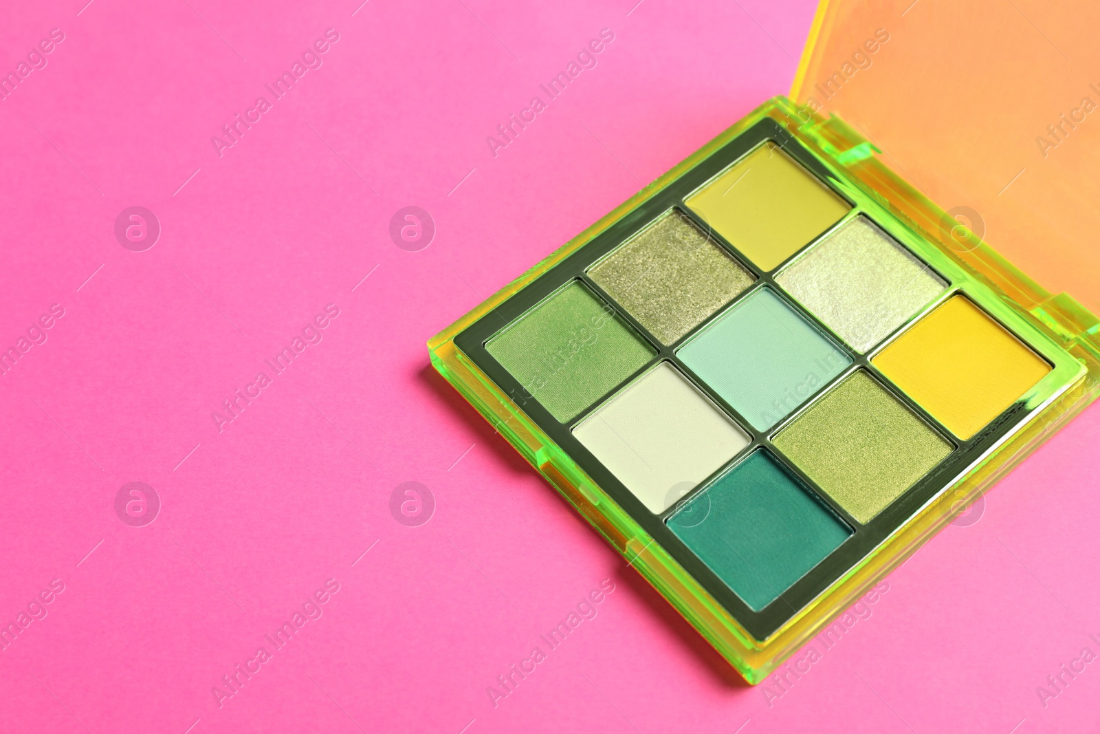 Photo of Colorful eyeshadow palette on pink background. Space for text