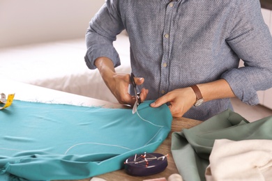 Tailor working with cloth at table in atelier