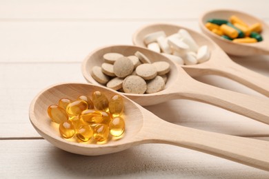 Spoons with different dietary supplements on white wooden table, closeup