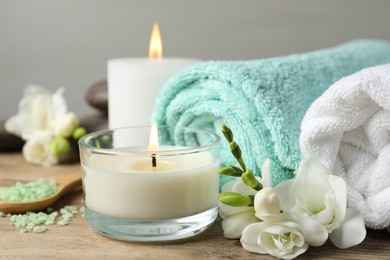 Photo of Beautiful composition with burning candles and different spa products on wooden table, closeup