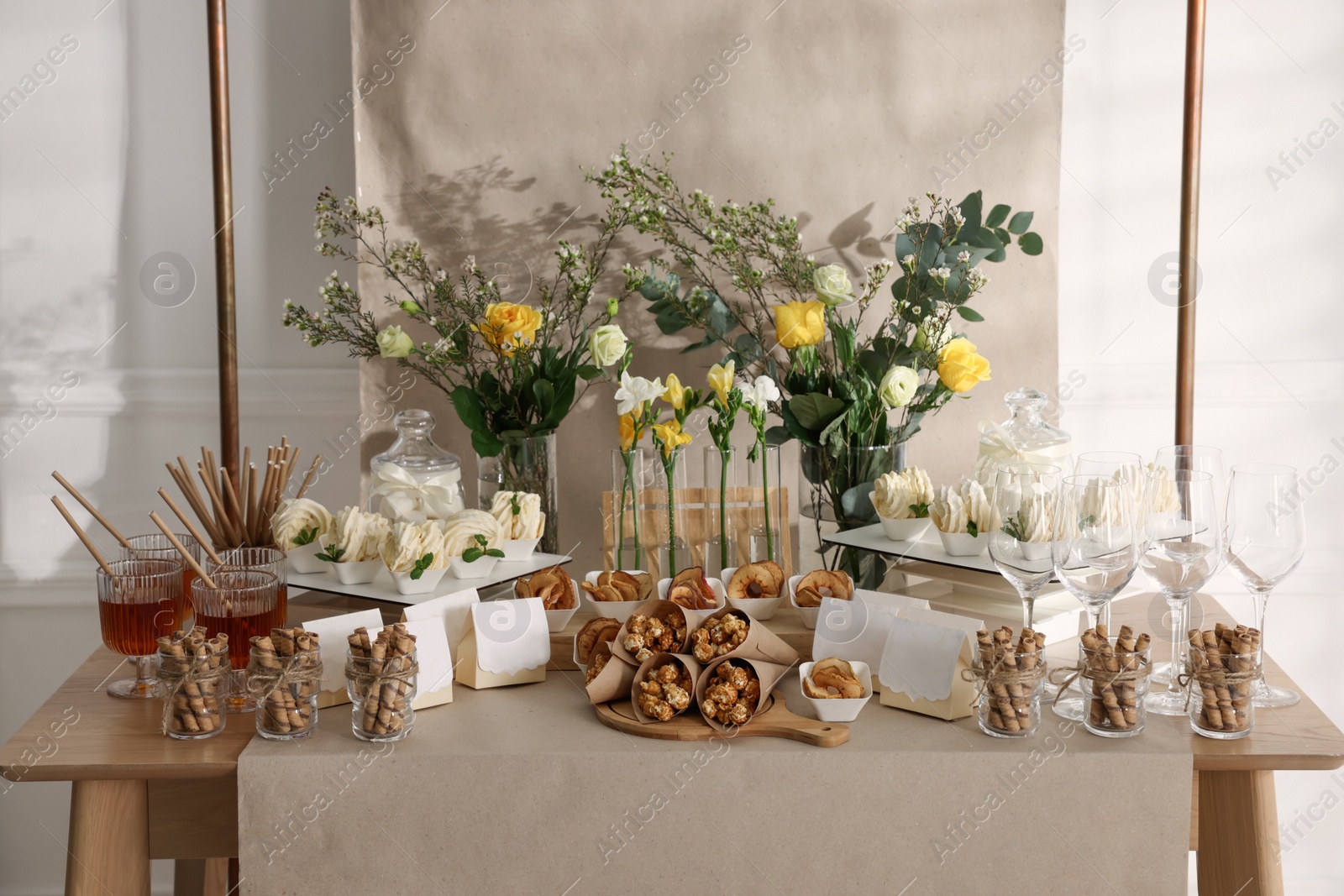 Photo of Delicious treats and glasses of drink on wooden table in room. Sweet buffet