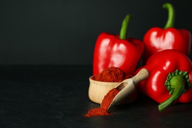 Photo of Paprika powder and fresh bell peppers on black table. Space for text