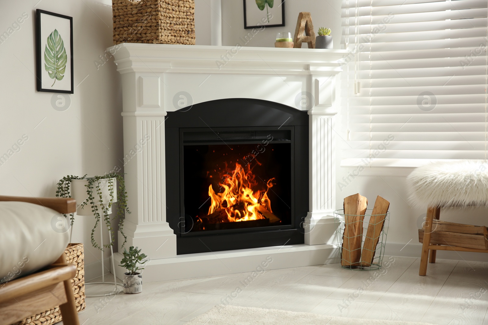 Photo of Bright living room interior with artificial fireplace and firewood in basket