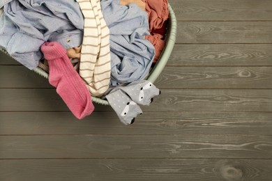 Photo of Laundry basket with clothes on dark grey wooden floor, top view. Space for text