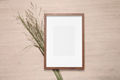 Photo of Empty photo frame and beautiful wildflowers on wooden background, flat lay. Mockup for design