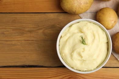 Freshly cooked homemade mashed potatoes and raw vegetables on wooden table, flat lay. Space for text