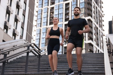 Photo of Healthy lifestyle. Happy couple running on steps outdoors, low angle view