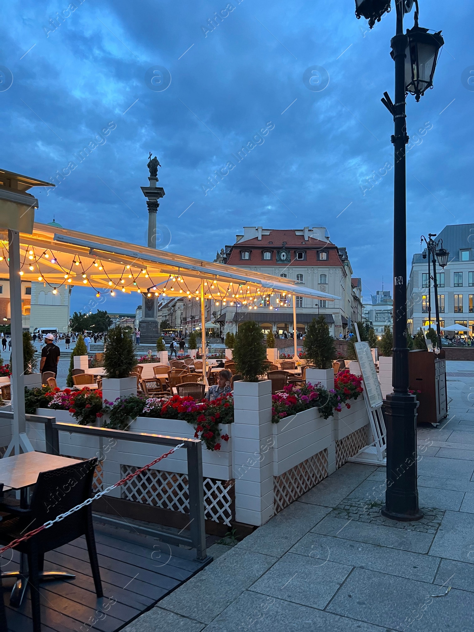 Photo of WARSAW, POLAND - JULY 15, 2022: Outdoor cafe terrace on Crowded Old Town Market Place in evening