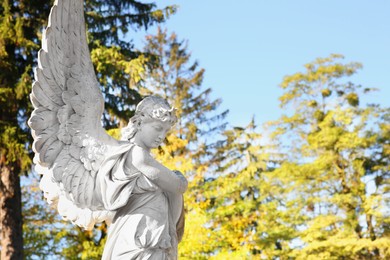 Beautiful statue of angel at cemetery, space for text