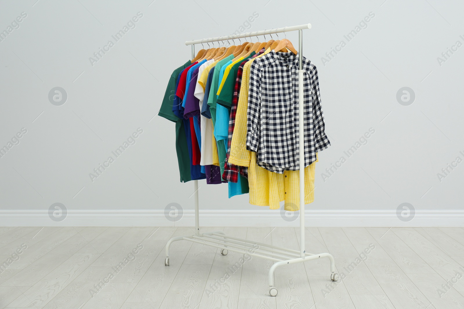 Photo of Rack with bright stylish clothes in room