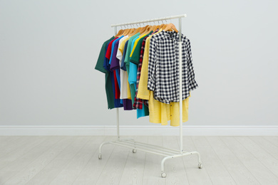 Rack with bright stylish clothes in room