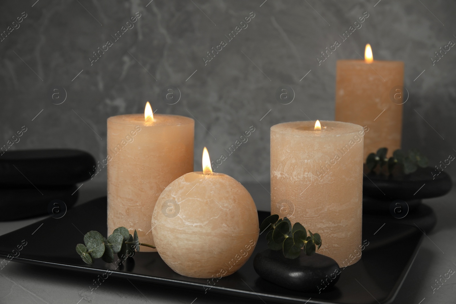 Photo of Composition with burning candles, spa stones and eucalyptus on grey background