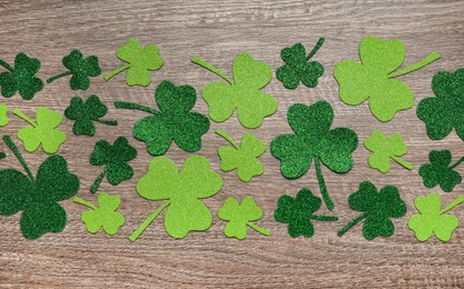 Photo of Decorative clover leaves on grey wooden table, flat lay. Saint Patrick's Day celebration