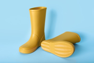 Photo of Pair of yellow rubber boots on light blue background