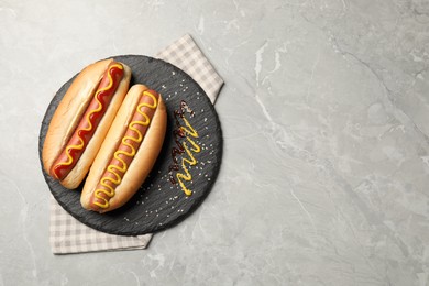 Photo of Delicious hot dogs with mustard and ketchup on light grey table, top view. Space for text