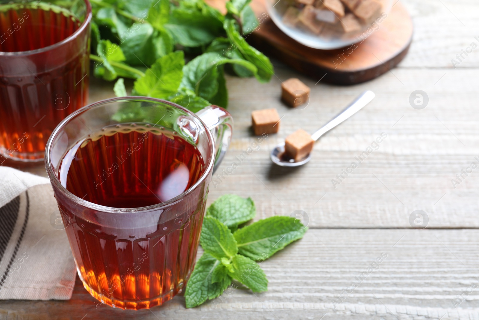 Photo of Cup with hot aromatic mint tea on wooden table, space for text