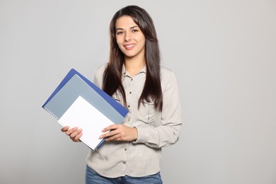 Photo of Happy young teacher with books on light grey background. Space for text