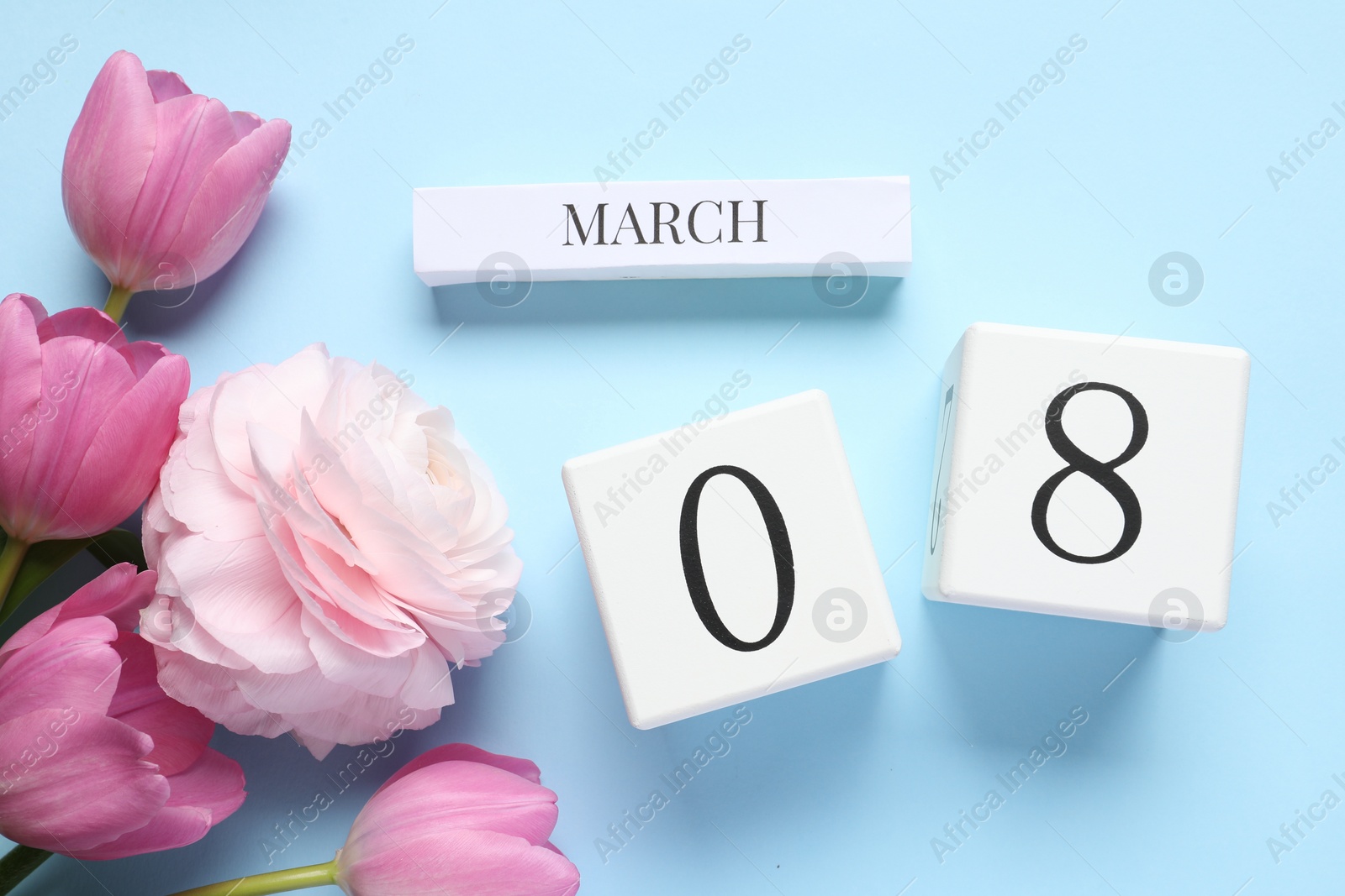 Photo of International Women's day - 8th of March. Wooden block calendar and beautiful flowers on light blue background, flat lay