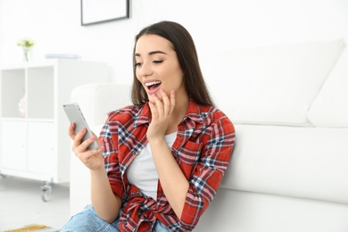 Photo of Attractive young woman using mobile phone at home