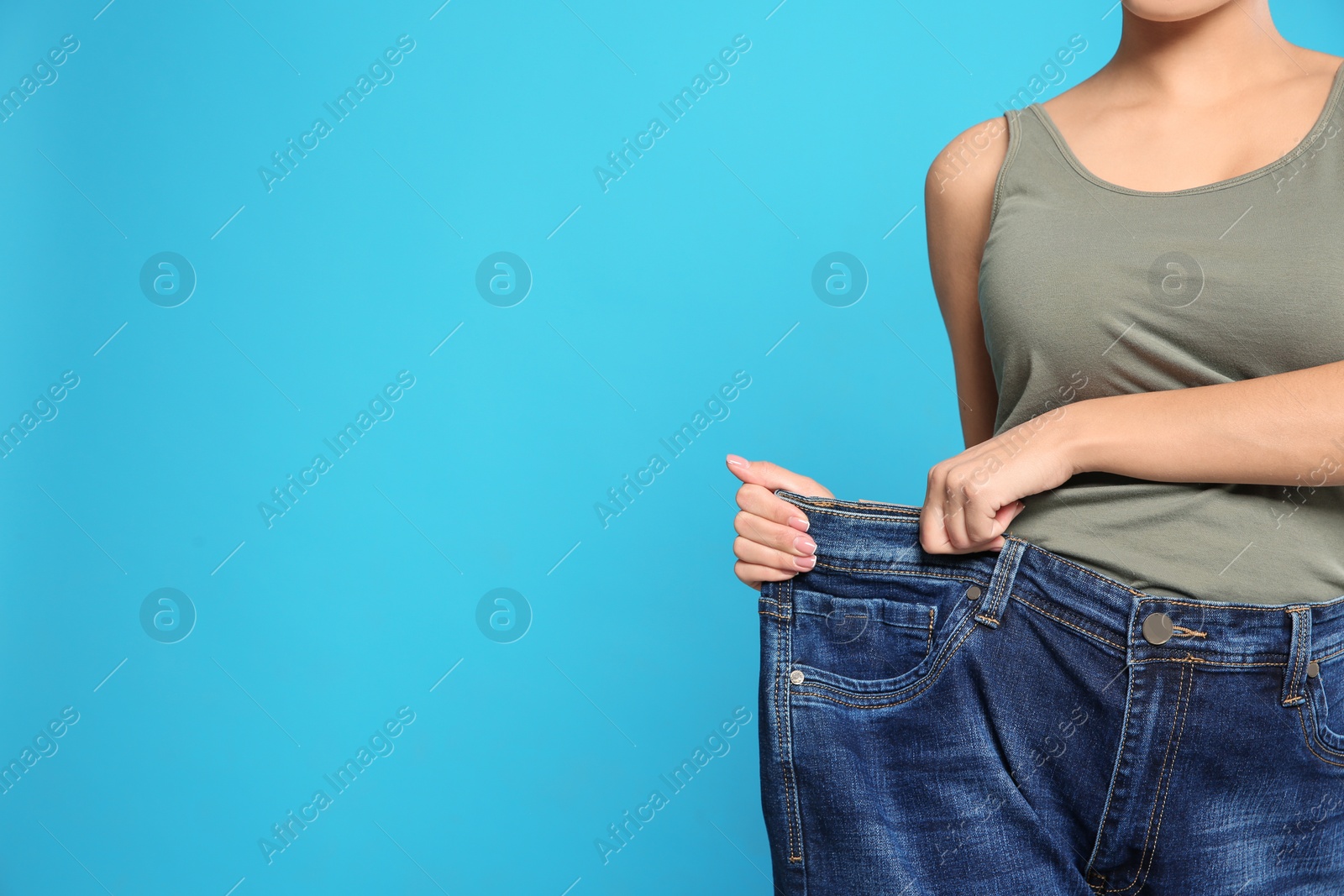 Photo of Slim woman in oversized jeans on color background, closeup view with space for text. Weight loss