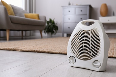 Photo of Modern electric fan heater on floor at home. Space for text