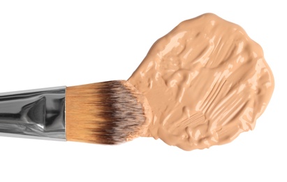 Sample of liquid foundation and makeup brush on white background, top view