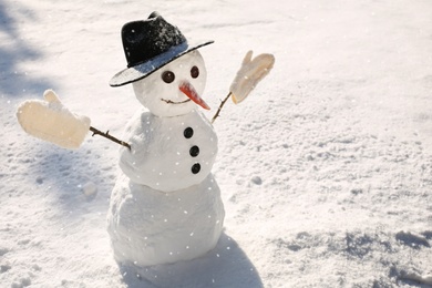 Photo of Funny snowman with hat and mittens outdoors on sunny day. Space for text