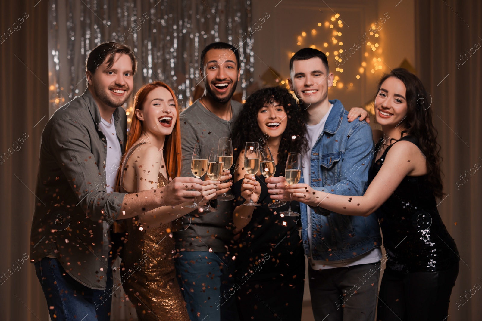 Photo of Happy friends with glasses of sparkling wine celebrating birthday indoors