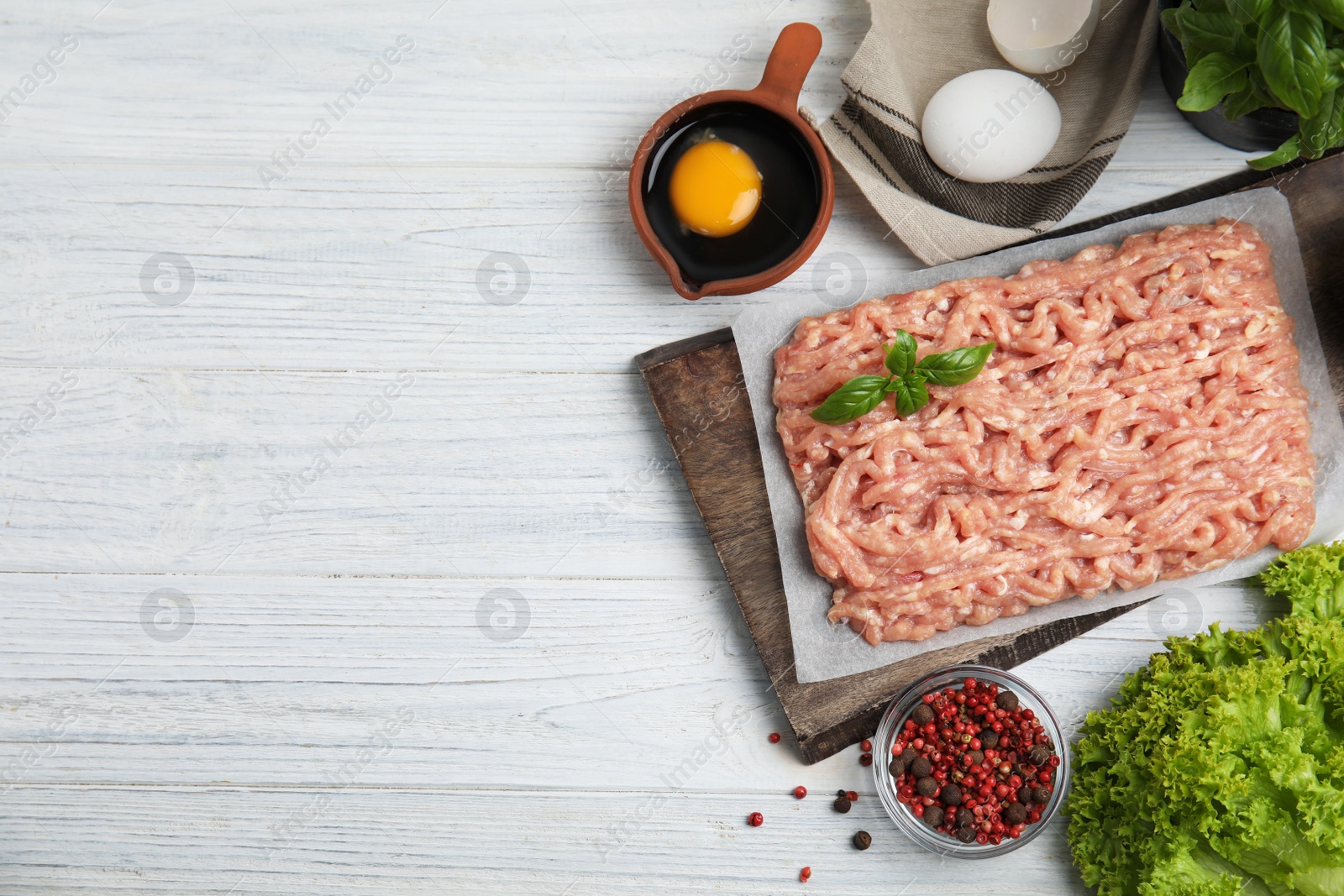 Photo of Raw chicken minced meat and ingredients on white wooden table, flat lay. Space for text