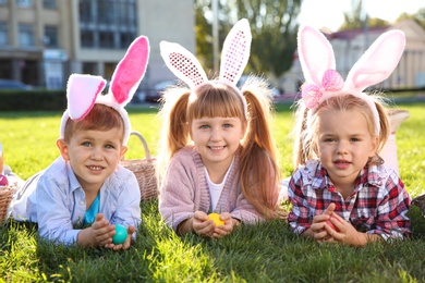 Cute little children with bunny ears and Easter eggs in park