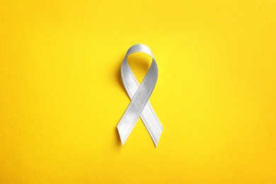 Photo of Grey ribbon on color background, top view. Cancer awareness