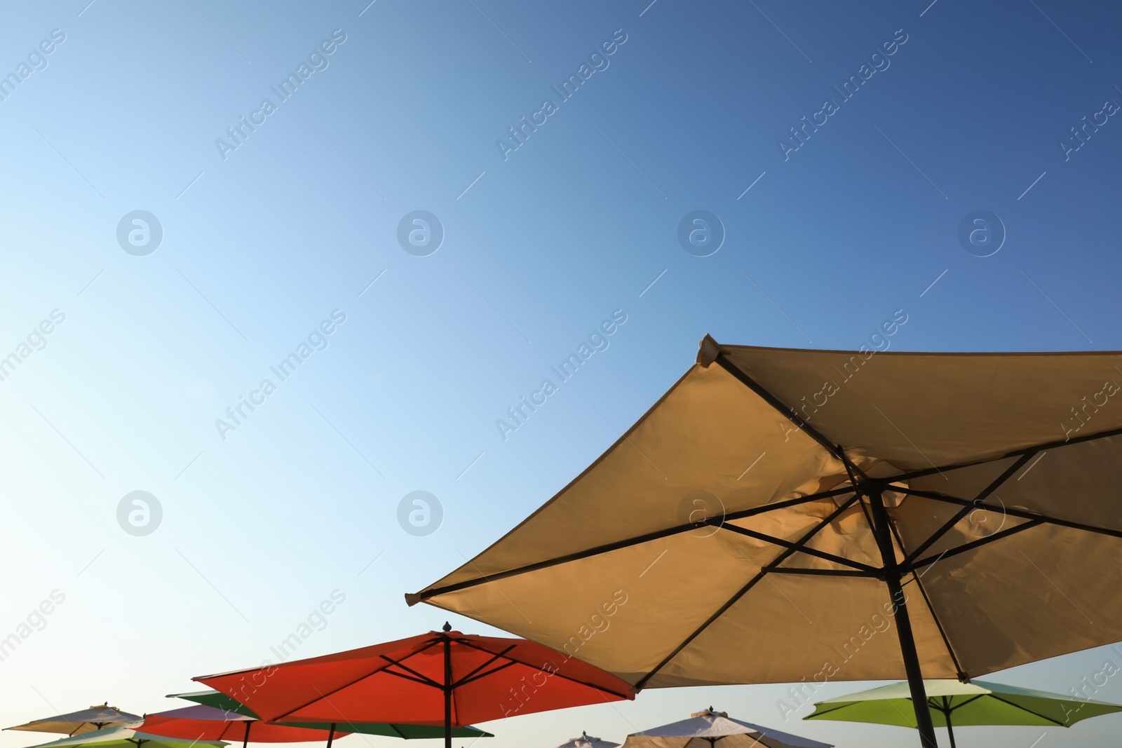 Photo of Colorful beach umbrellas against blue sky on sunny day