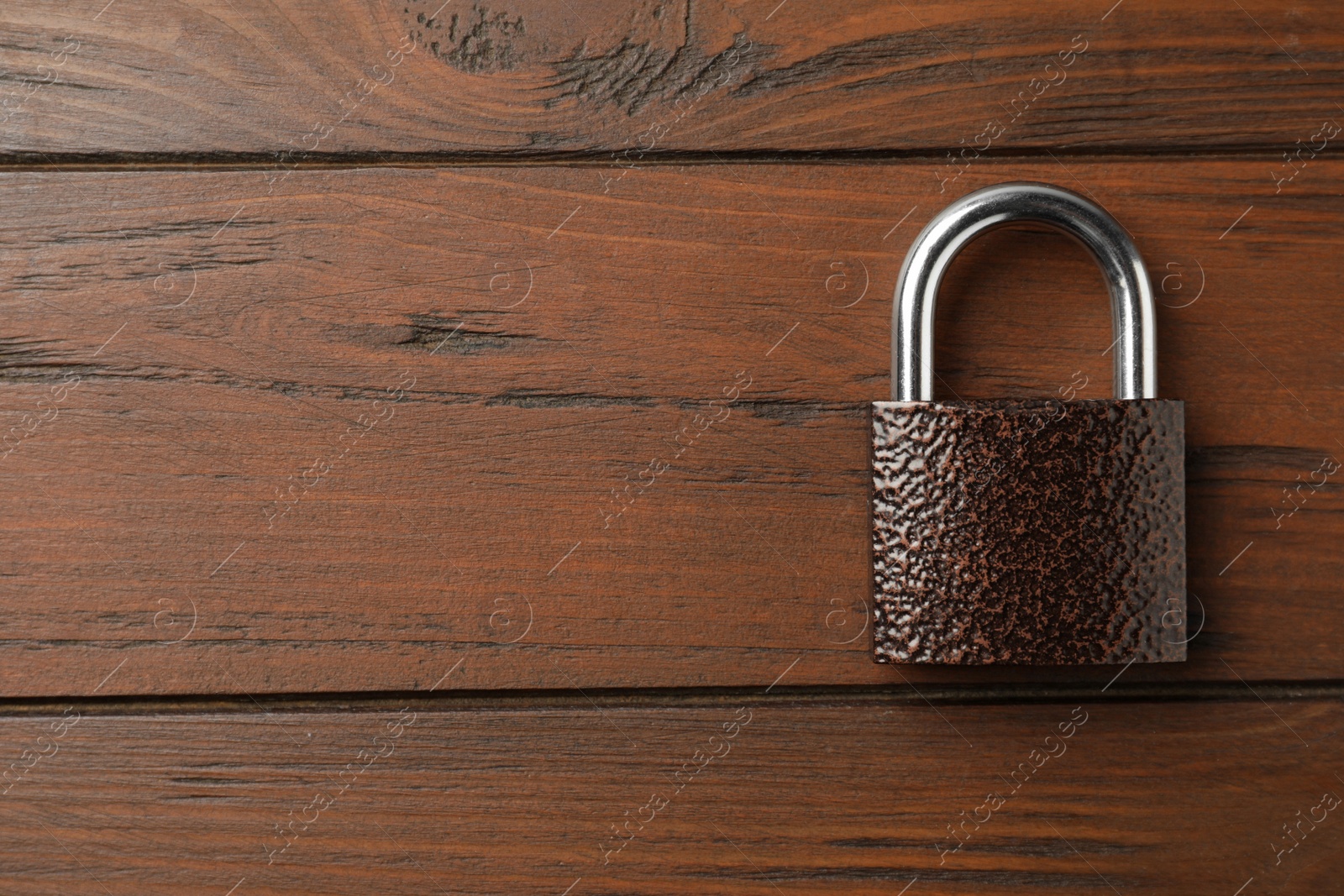 Photo of Steel padlock and space for text on wooden background, top view. Safety concept