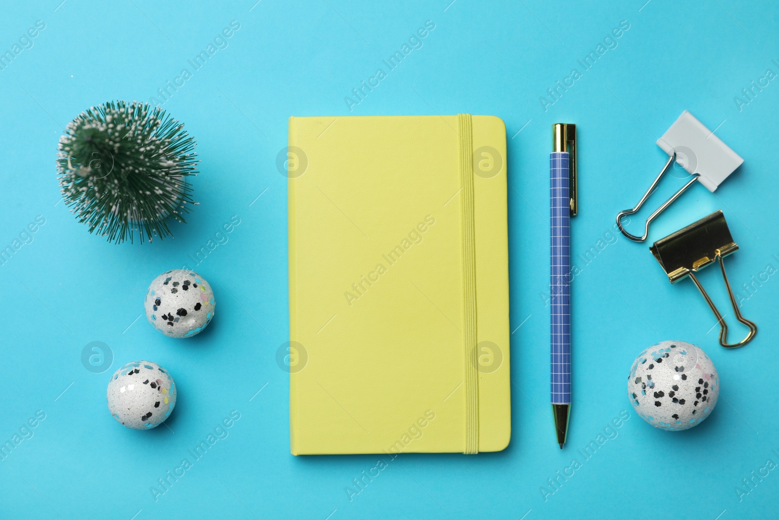 Photo of Yellow planner and Christmas decor on light blue background, flat lay