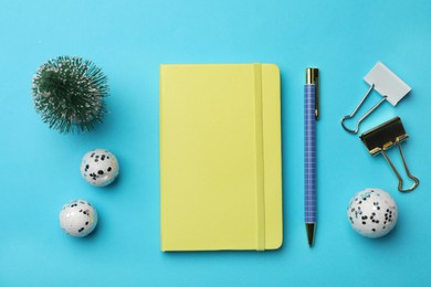 Yellow planner and Christmas decor on light blue background, flat lay