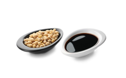 Dishes with soy sauce and beans on white background