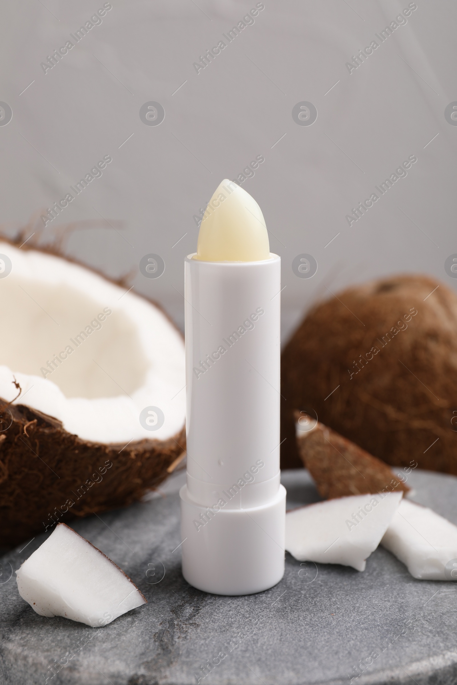 Photo of Lip balm and coconut on grey table