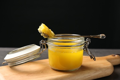 Photo of Jar and spoon with clarified butter on wooden board