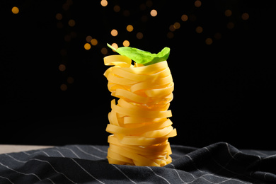 Photo of Uncooked tagliatelle pasta on fabric against blurred lights