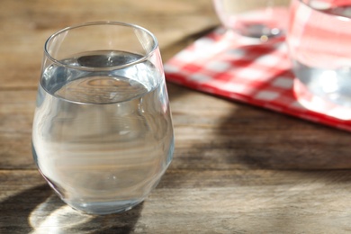 Photo of Glass of water on wooden table, closeup with space for text. Refreshing drink