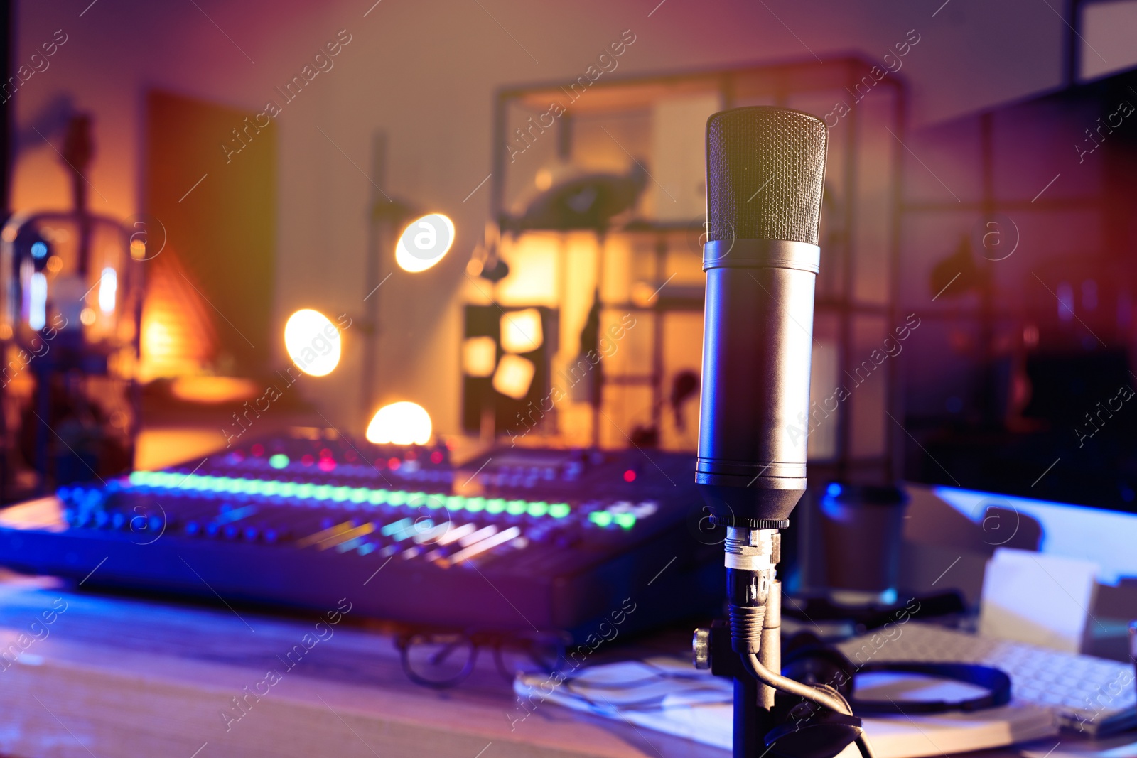 Photo of Microphone near table with professional mixing console in radio studio