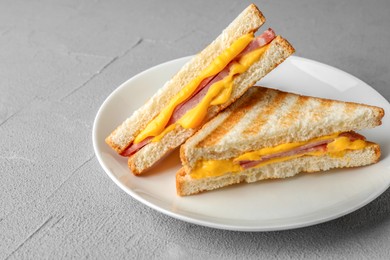 Tasty sandwiches with ham and melted cheese on grey textured table, closeup